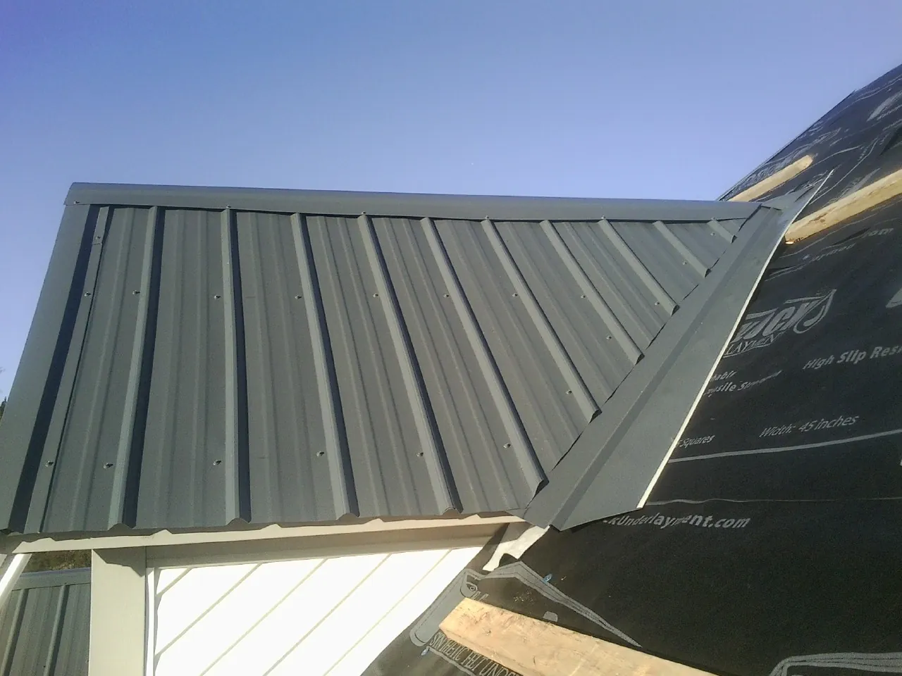 Gray metal roof panels going on over a garage gable in White Earth