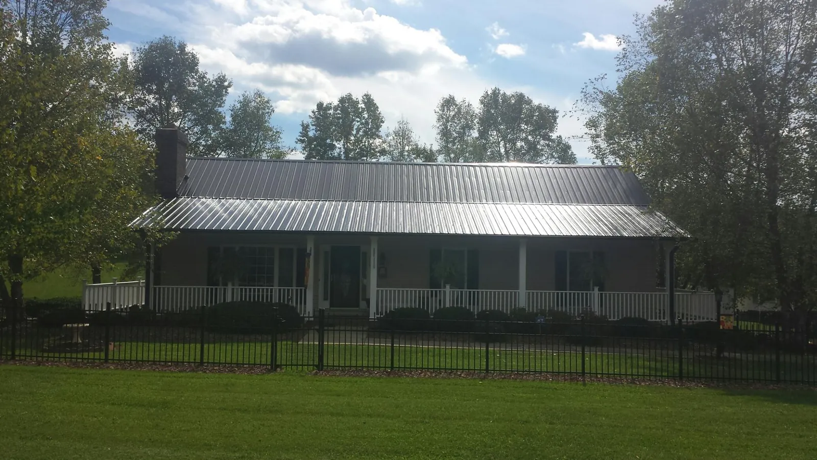 Gray metal roof on a brick ranch with a full width front porch — Gutter Guard Installation work by our crew in White Earth