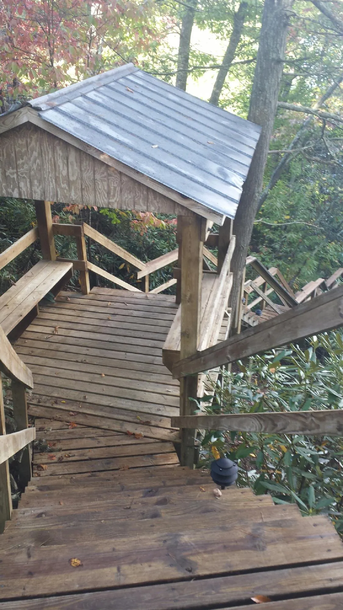 Metal roofed shelter over wooden steps on a wooded walkway — Skylight Repair & Installation work by our crew in White Earth
