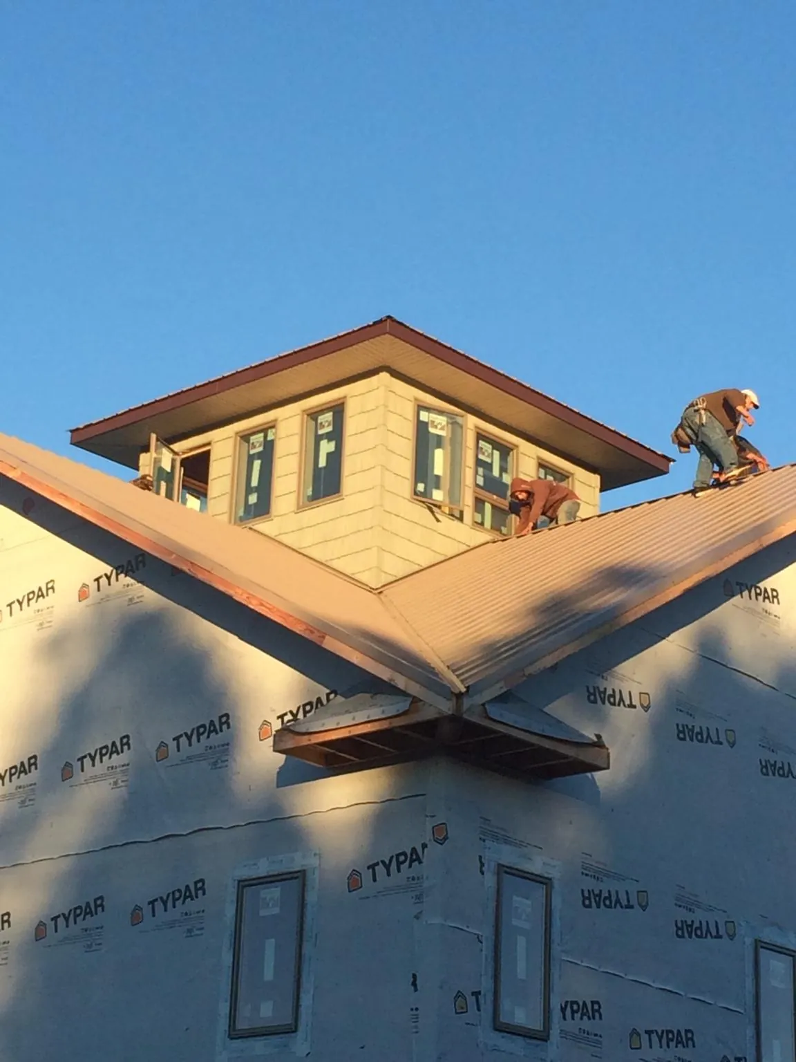 Roofers working around a rooftop cupola on a new metal roof at sunset — Roof Waterproofing in White Earth by Roofing Brothers